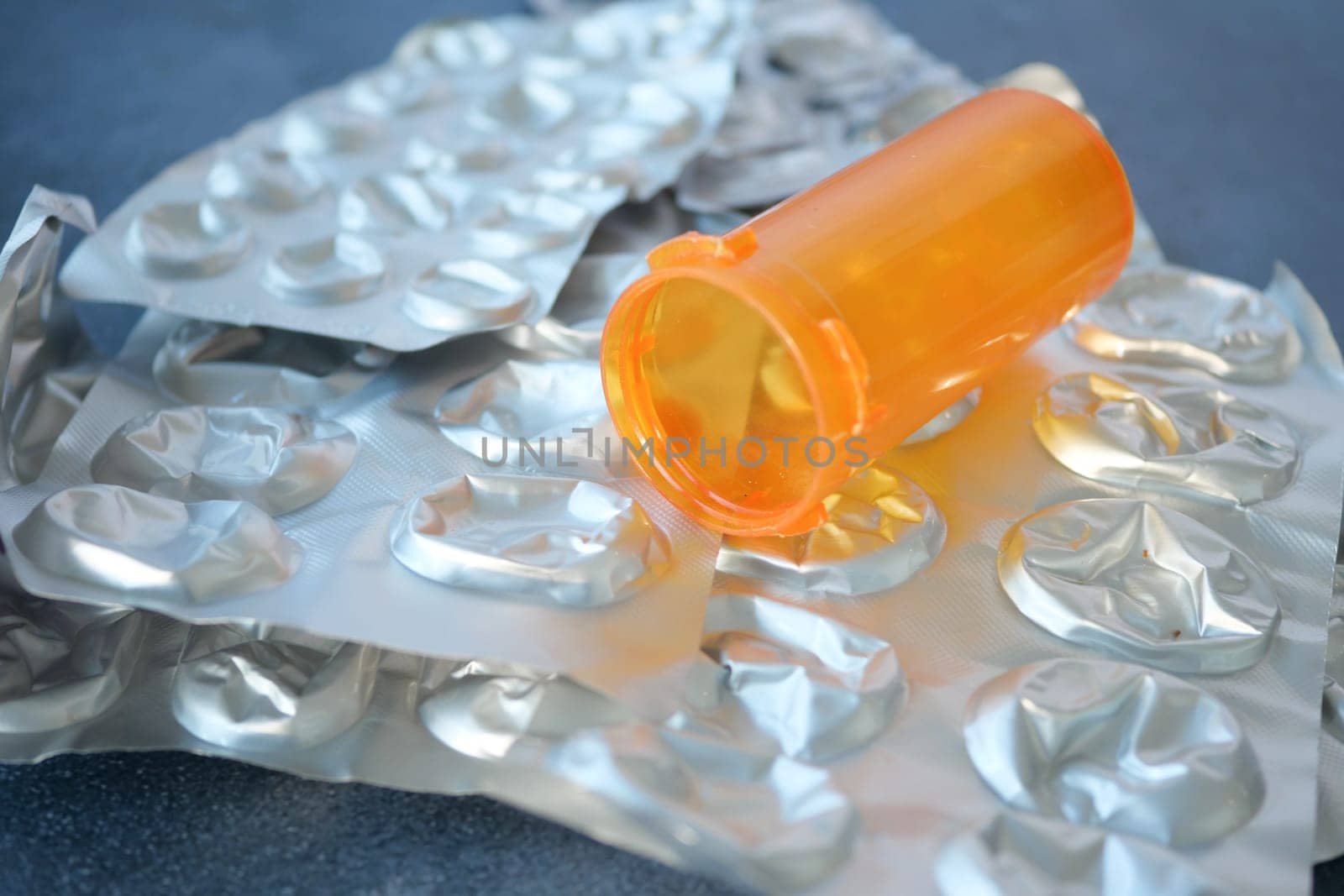 Orange prescription bottle spills out empty blister packs on surface.