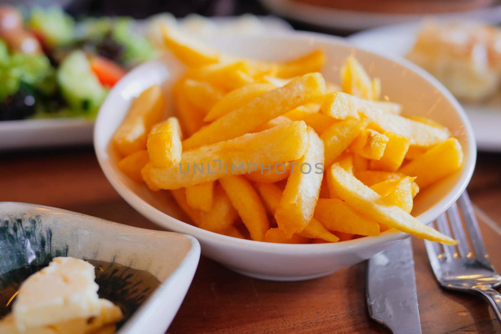 Delicious fries served in a bowl alongside a fresh salad and bread.
