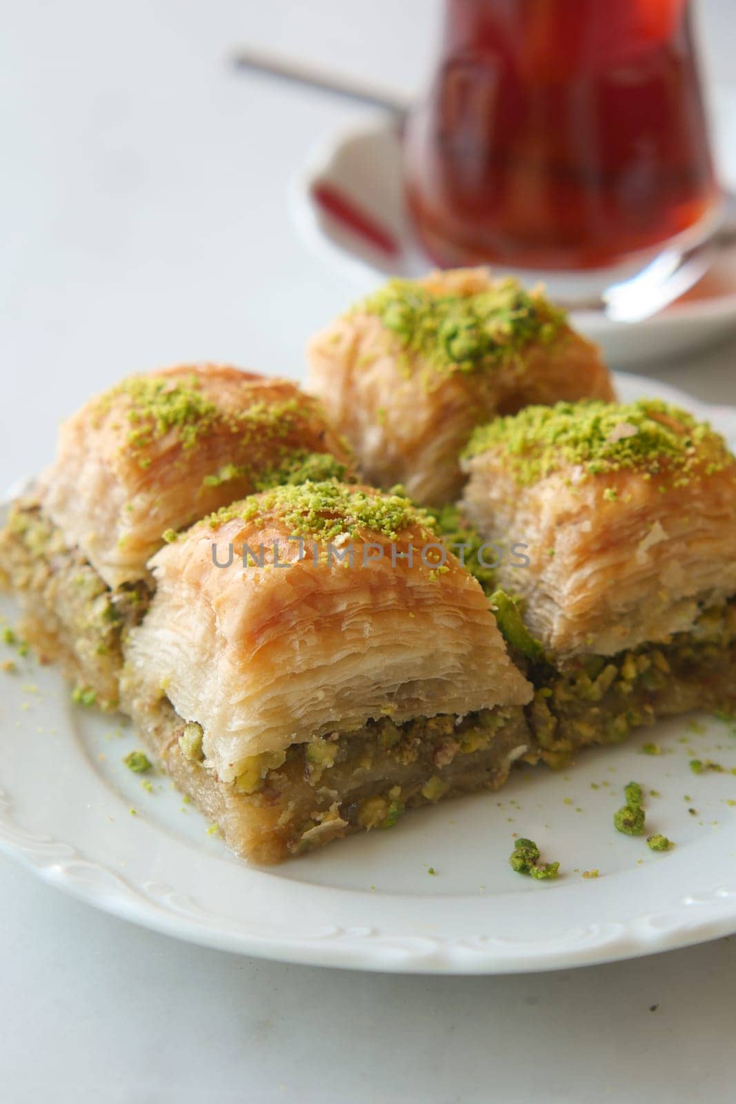 Delicious pieces of baklava topped with pistachios accompanied by tea.