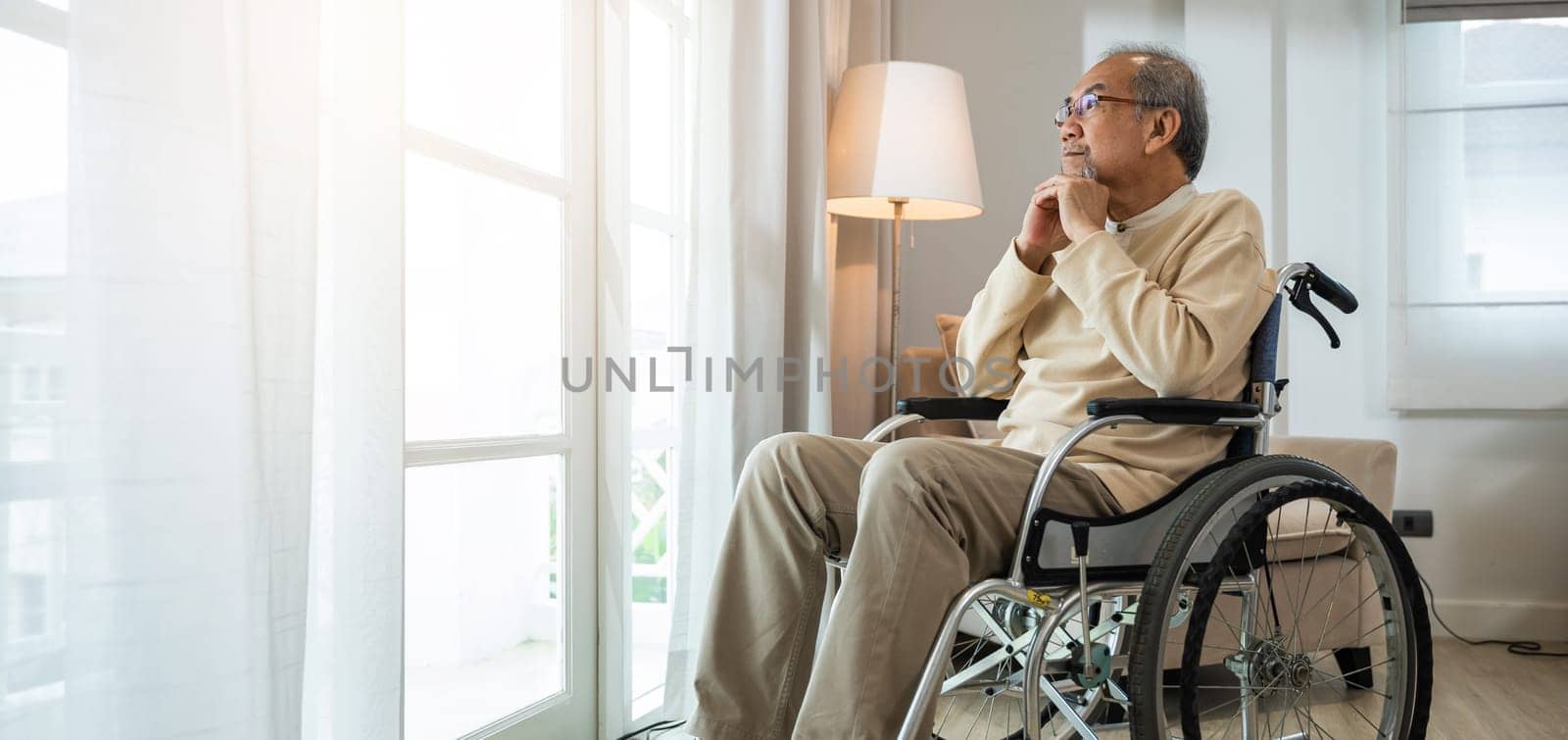 Lonely older thoughtful sad old man look outside windows in bedroom at retirement home, Asian senior man disabled feel depressed lonely sitting alone in wheelchair looking through window at hospital