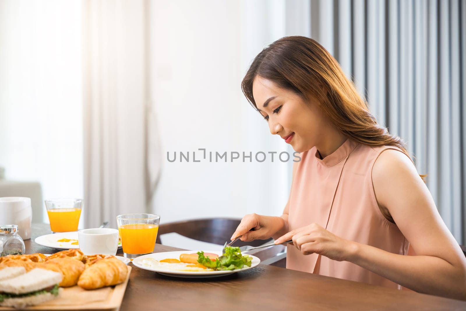 Asian young woman sitting kitchen table food having eating healthy breakfast at home, female eat fresh breakfast served food with beverage before go to work in the morning at home