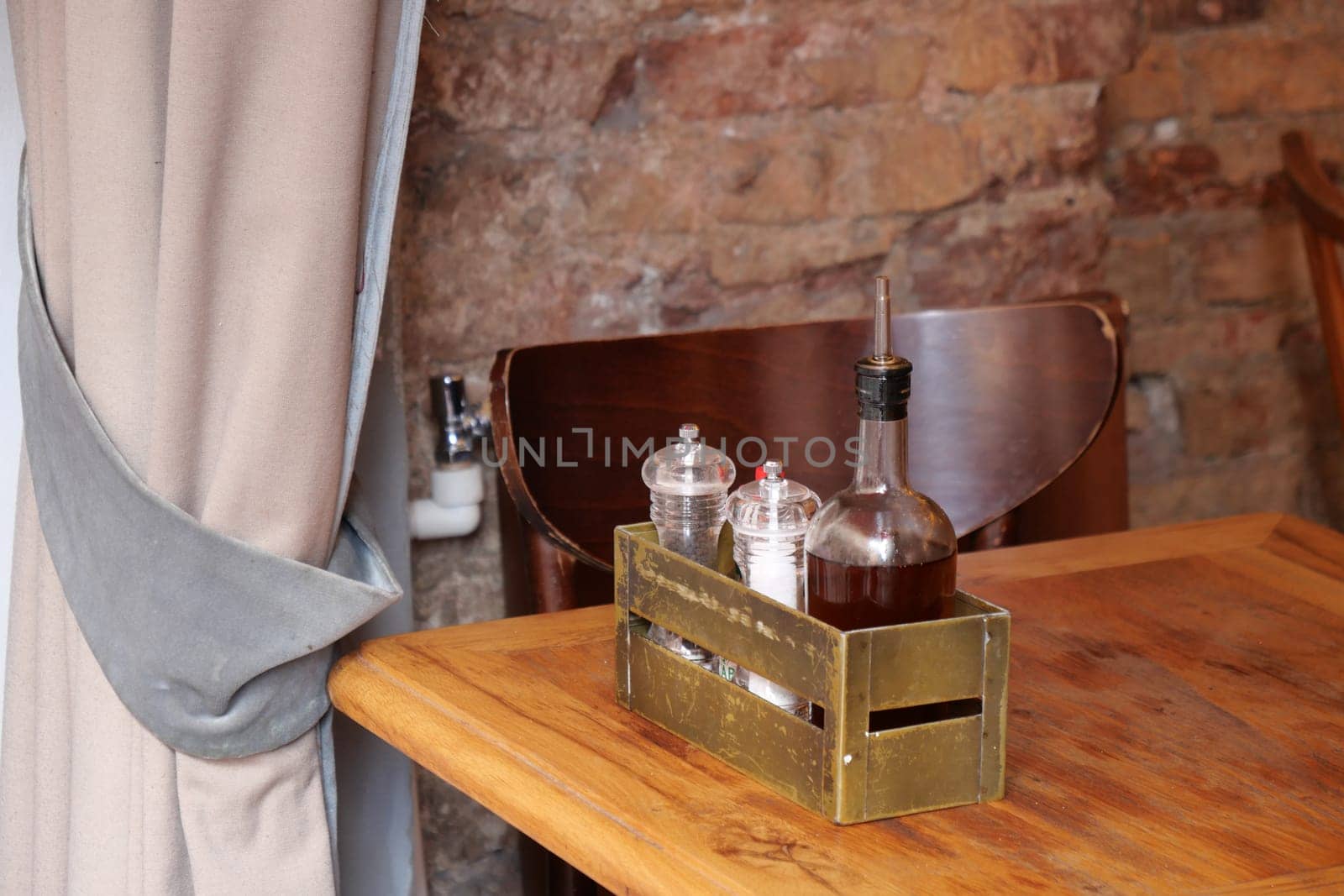 A rustic wooden table holds a container with condiments and sauce.