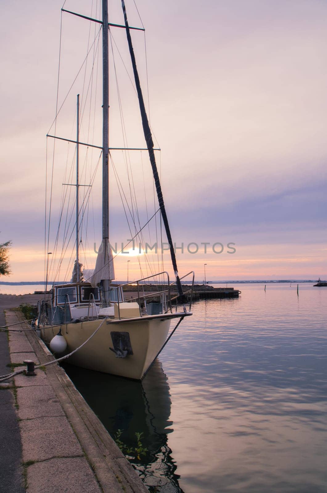 Sailing ship in the harbor of lake Vaettern at sunset. Lighthouse in the background. Landscape shot from Scandinavia