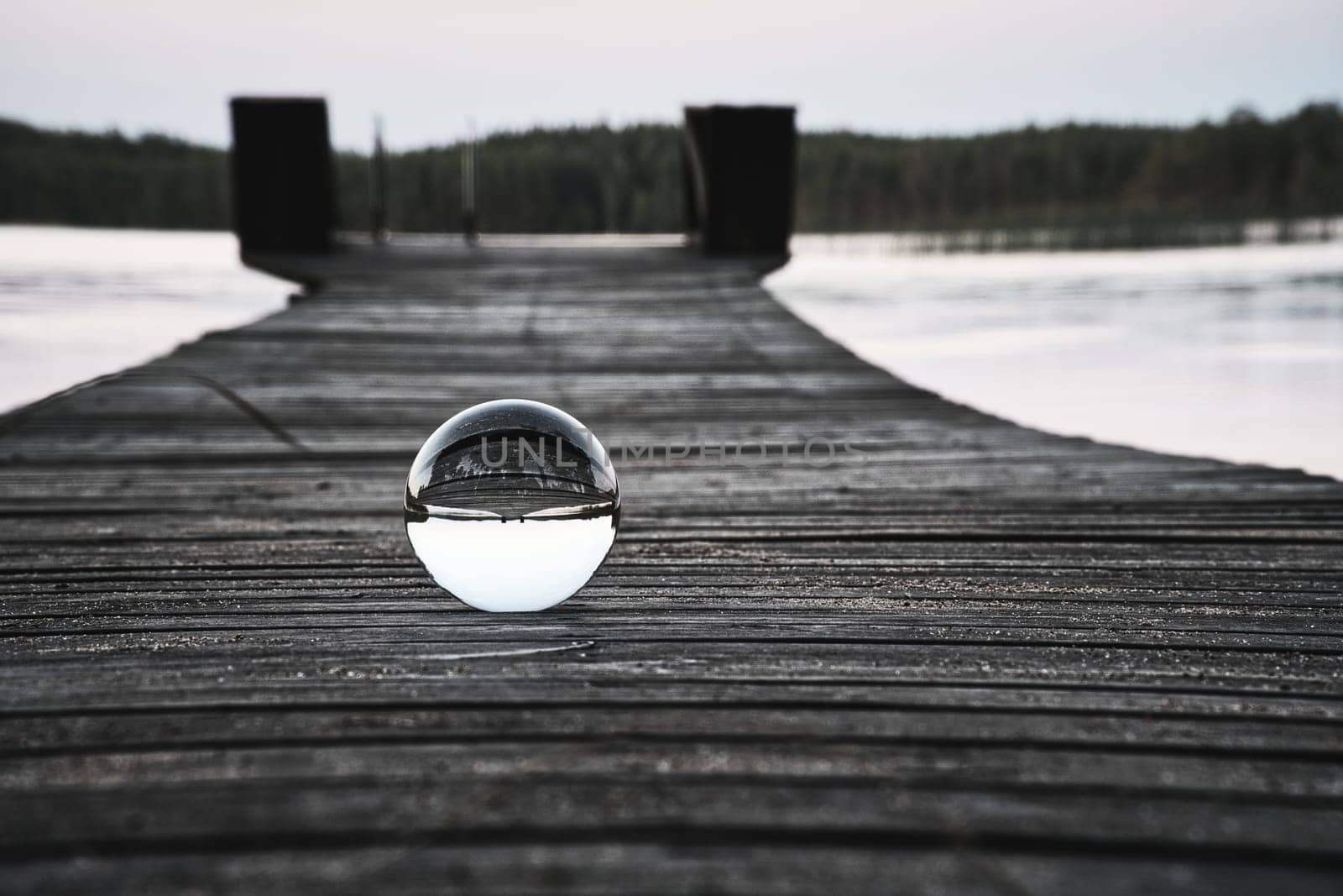 Glass ball on a wooden walkway on a Swedish lake at the blue hour. Nature shot from Scandinavia