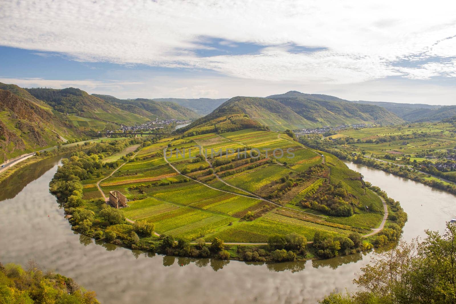 View of a riverbend of the Moselle River in the Eifel village of Bremm in Germany in summer. Seen from the Calmont vineyards with blue sky.