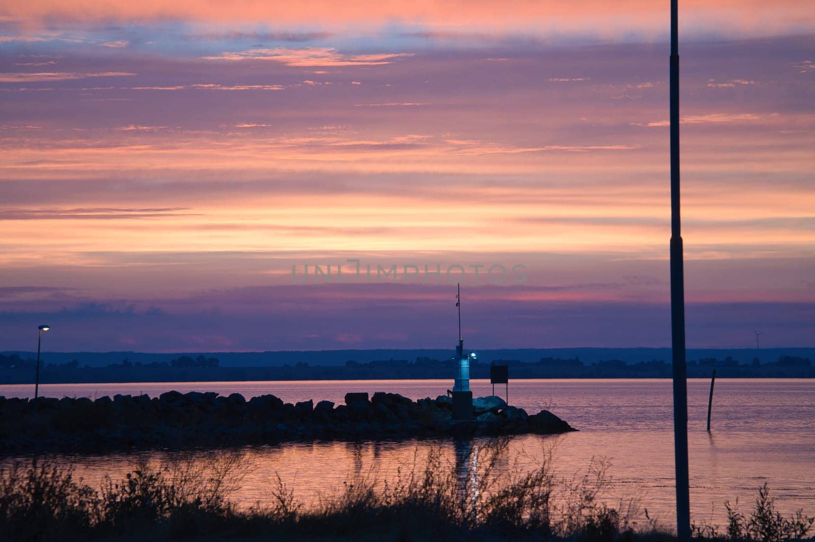 Sunset in Sweden at the harbor of lake Vaettern. Lighthouse in the background at dusk. Landscape shot in Scandinavia.