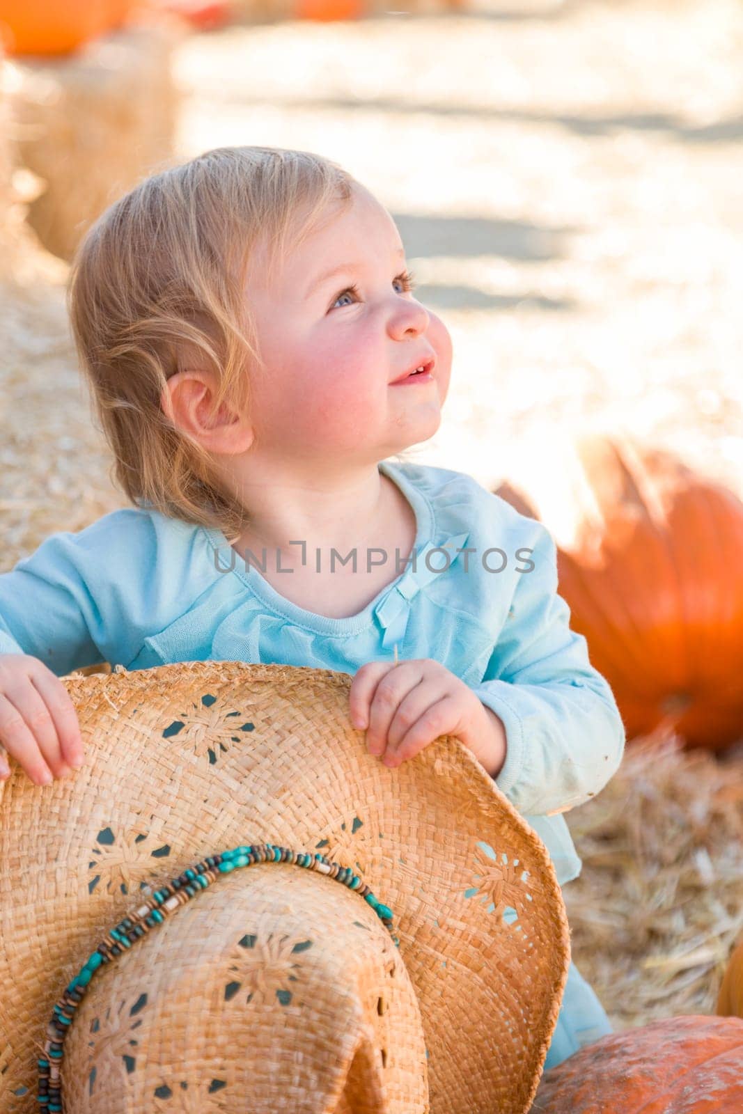 Adorable Baby Girl with Cowboy Hat in a Country Rustic Setting at the Pumpkin Patch.