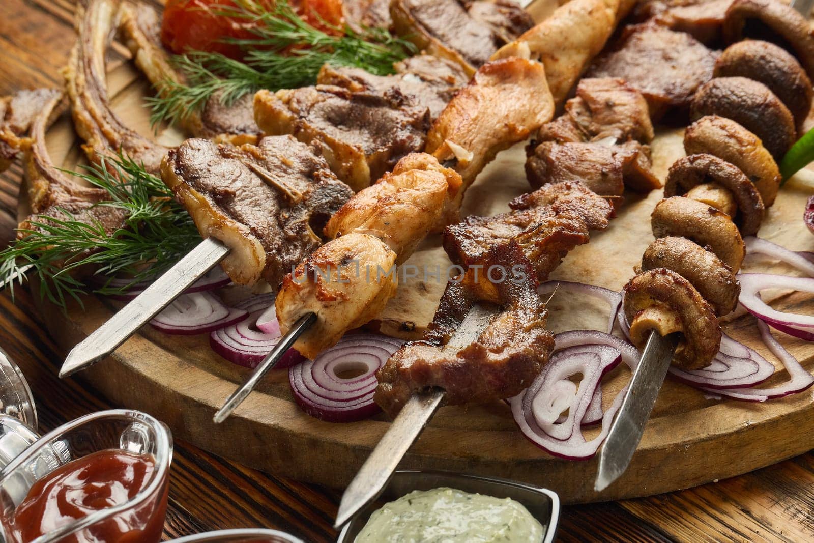 Various grilled meats. Shashlik from different meats on barbecue skewers with vegetables and lavash on wooden board. Top view. Food background. Serving food