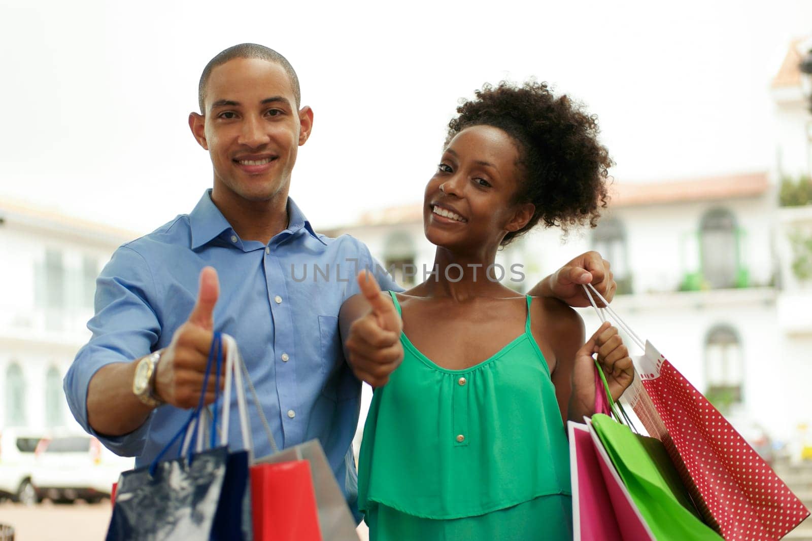 Portrait of black tourist heterosexual couple in Casco Antiguo - Panama City with shopping bags. The man and his girlfriend smile at the camera doing ok sign