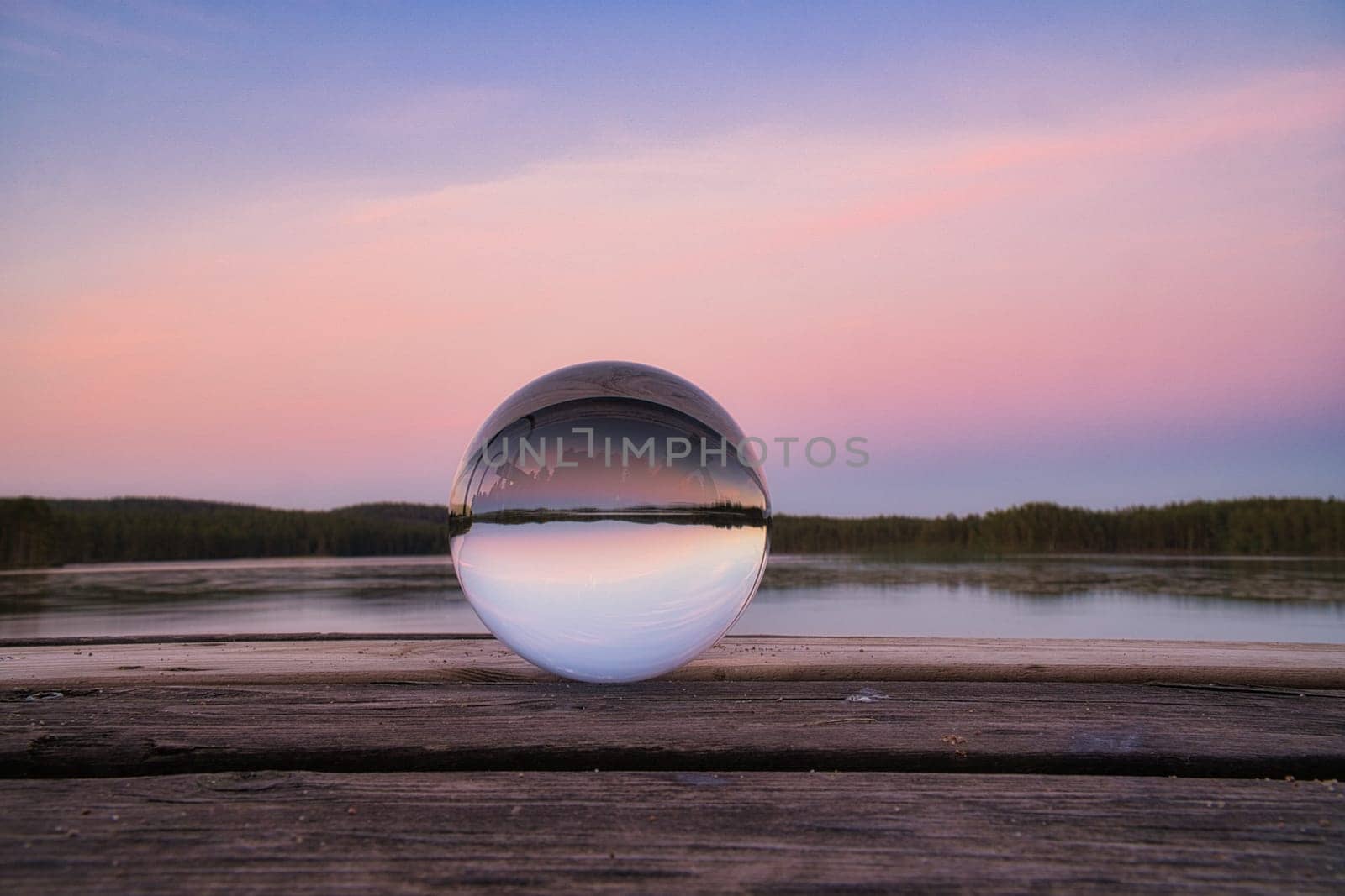 Glass ball on a wooden pier at a Swedish lake at evening hour. Nature shot from Scandinavia