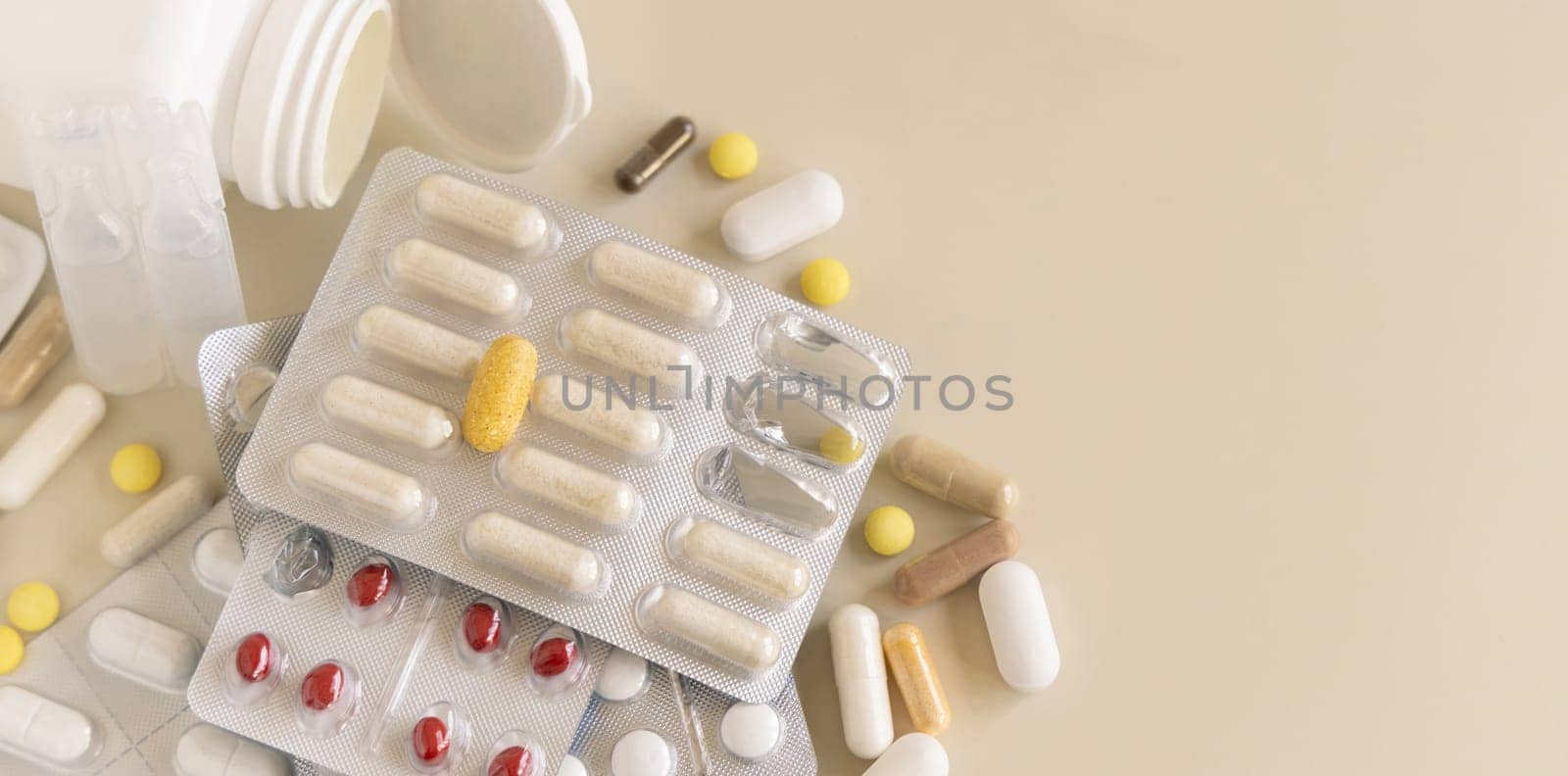 Mix of pills and capsules in a aluminum and plastic blisters with some missing pills already used on light beige close up, copy space. Preventive medicine and healthcare, dietary supplements
