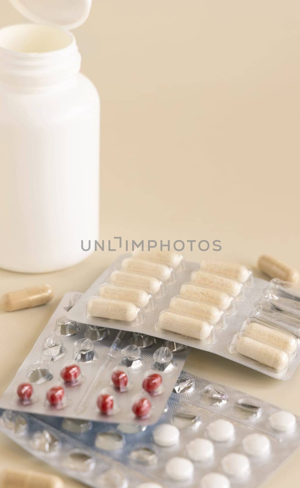 Mix of pills and capsules in a aluminum and plastic blisters with some missing pills already used on light beige close up, copy space. Preventive medicine and healthcare, dietary supplements