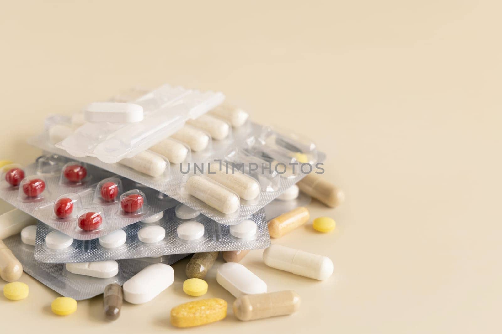 Mix of pills and capsules in a aluminum and plastic blisters with some missing pills already used on light beige close up. Preventive medicine and healthcare, taking dietary supplements and vitamins