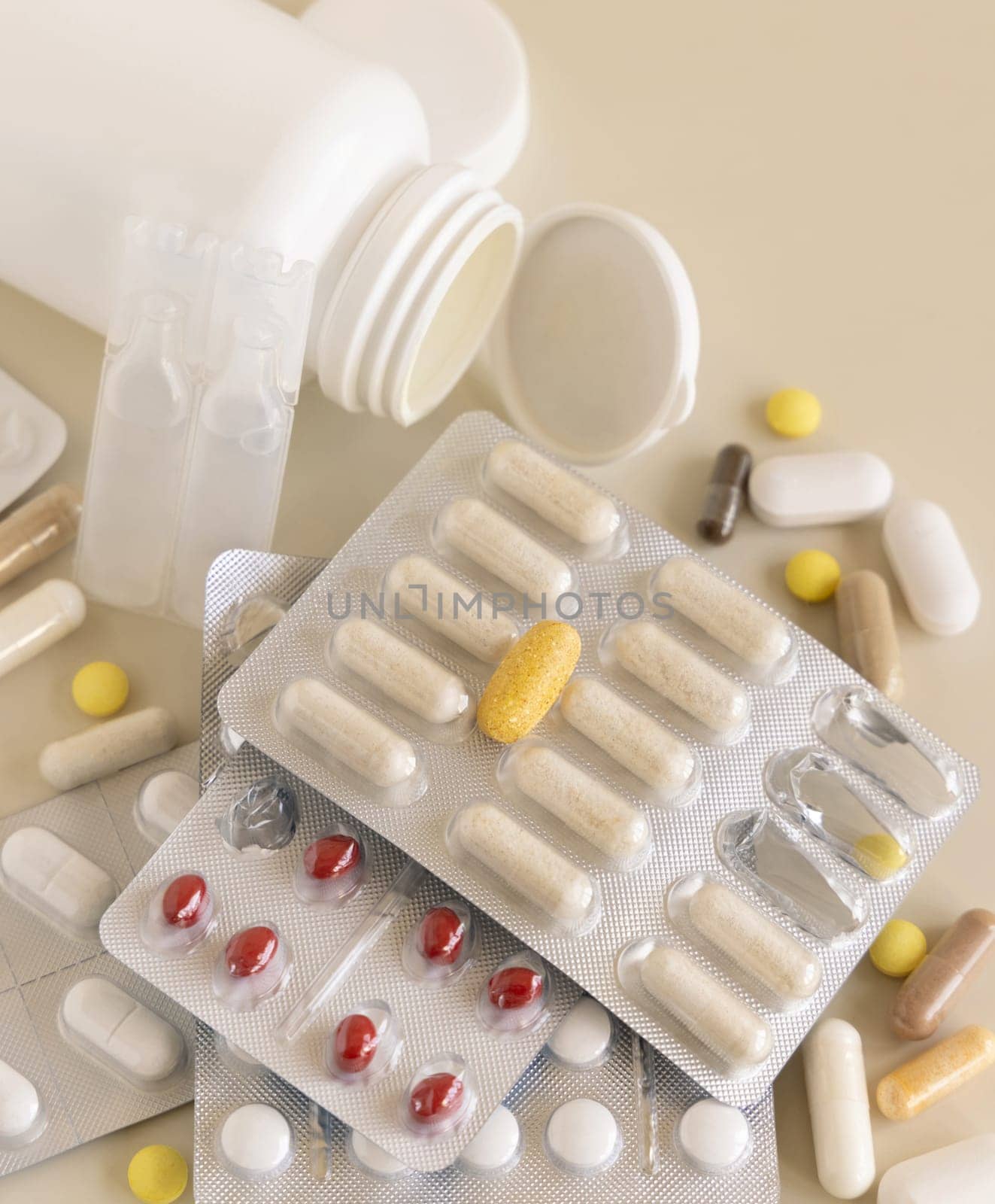 Mix of pills and capsules in a aluminum and plastic blisters with some missing pills already used on light beige close up. Preventive medicine and healthcare, taking dietary supplements and vitamins