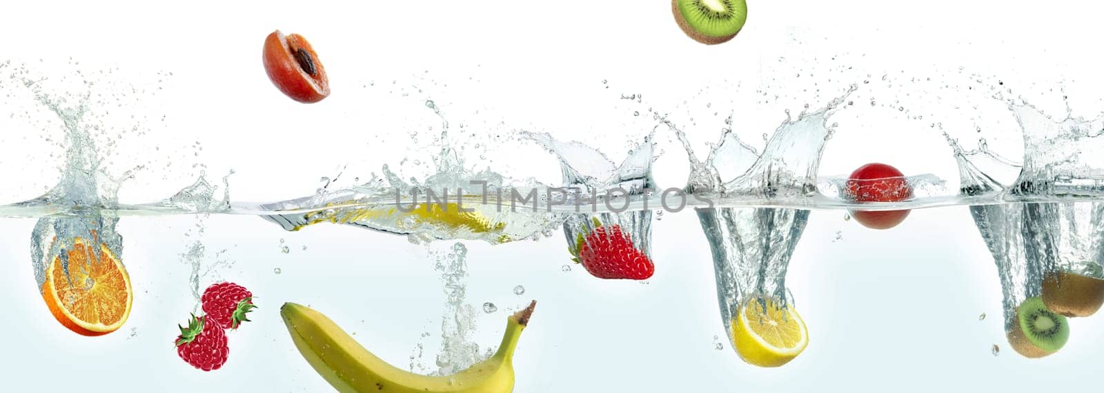 Various fruits splashing in water. Side panoramic view on white background.