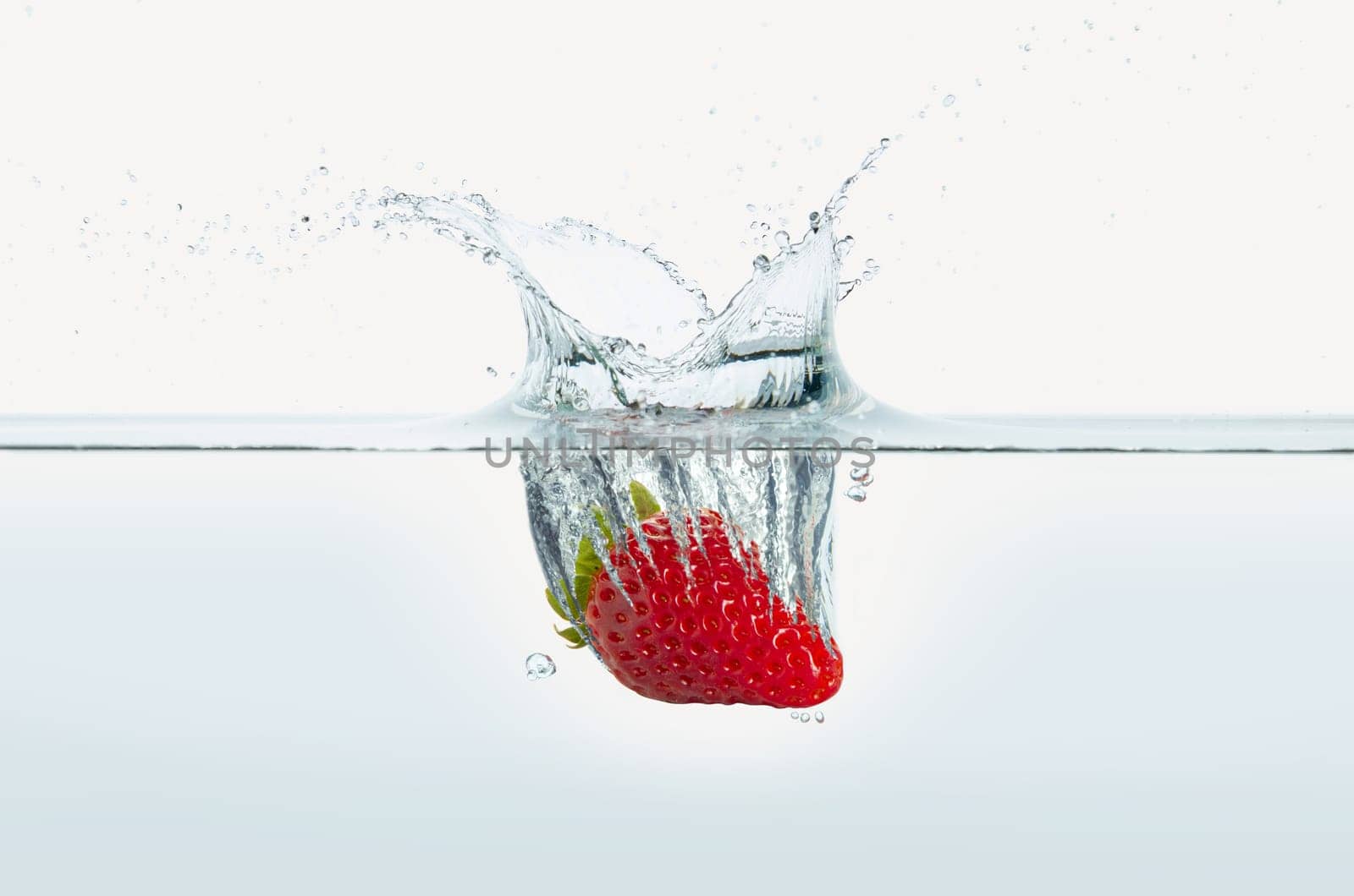 Strawberry splashing in water. Side view on white background.