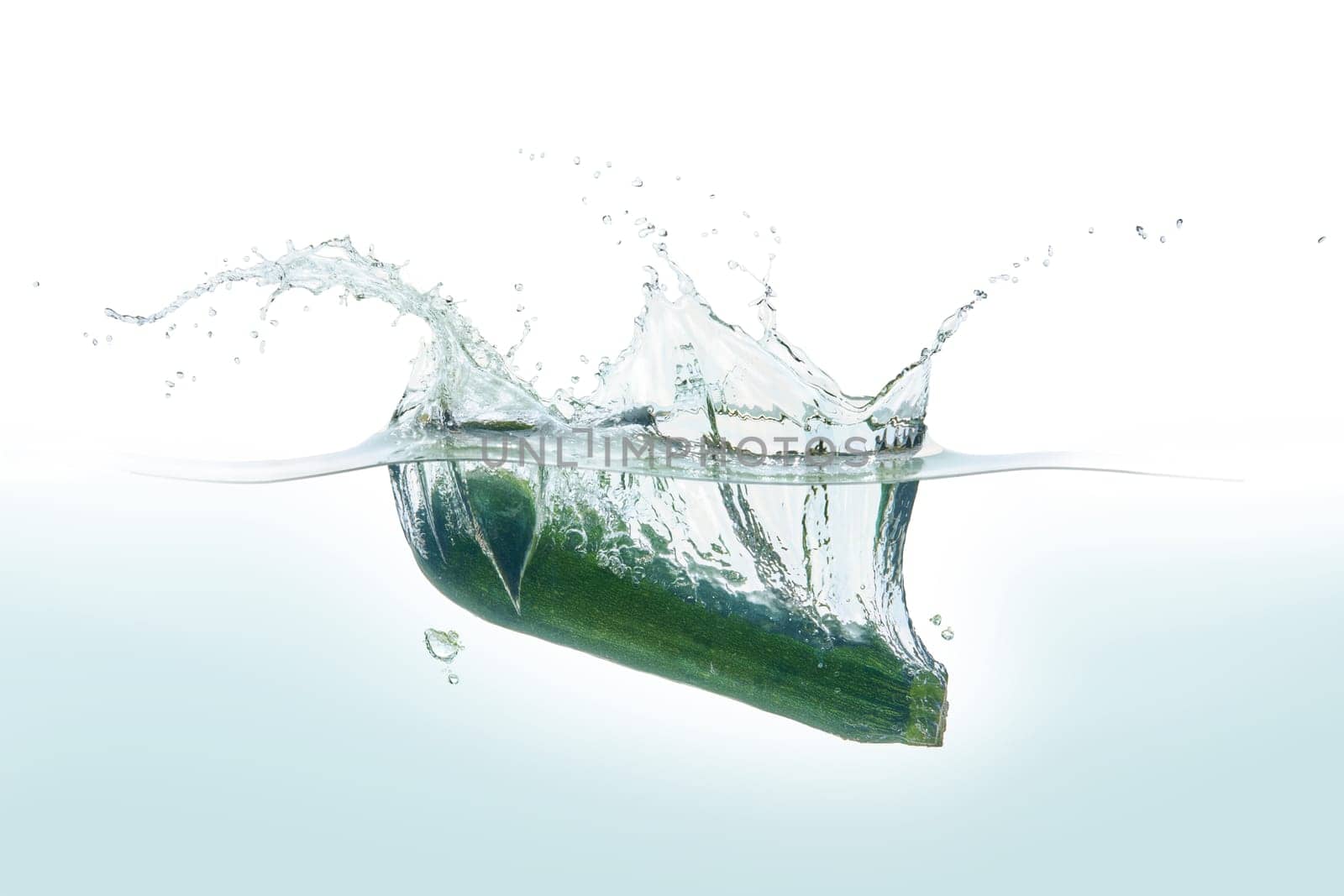Zuchini splashing in water. Side view on white background.