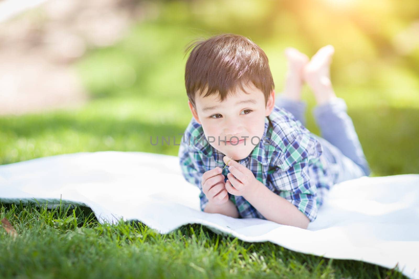 Mixed Race Chinese and Caucasian Young Boy Relaxing Outside On The Grass