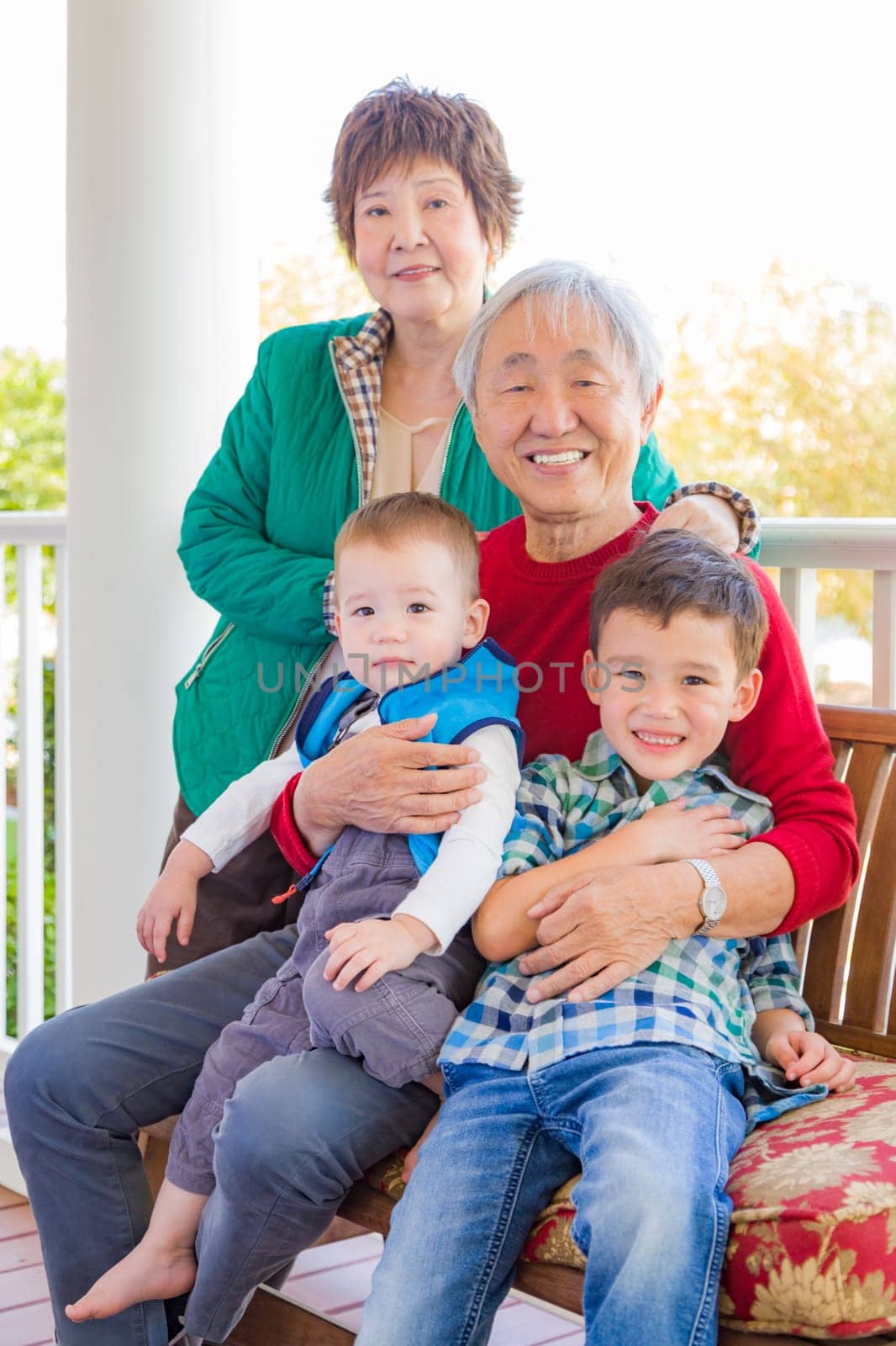 Senior Adult Chinese Couple Sitting With Their Mixed Race Grandchildren