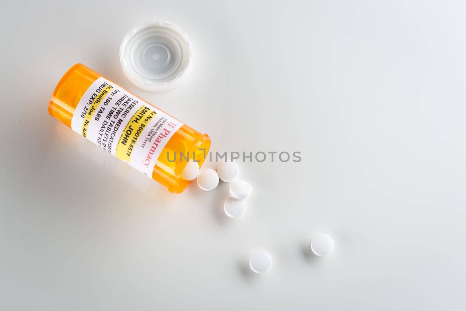Non-Proprietary Medicine Prescription Bottle and Spilled Pills  Over Head on Grey Background.