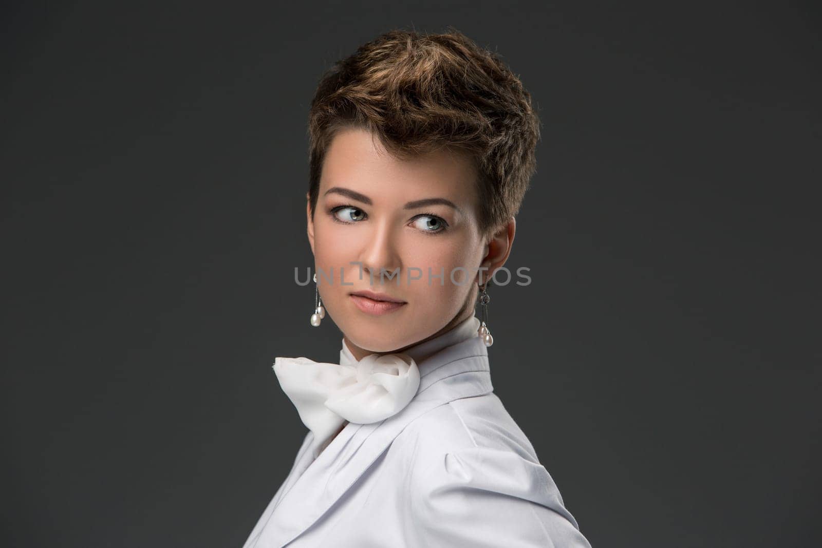 portrait of an elegant young doctor in a white coat and a white scarf, tied in a bow against a dark background