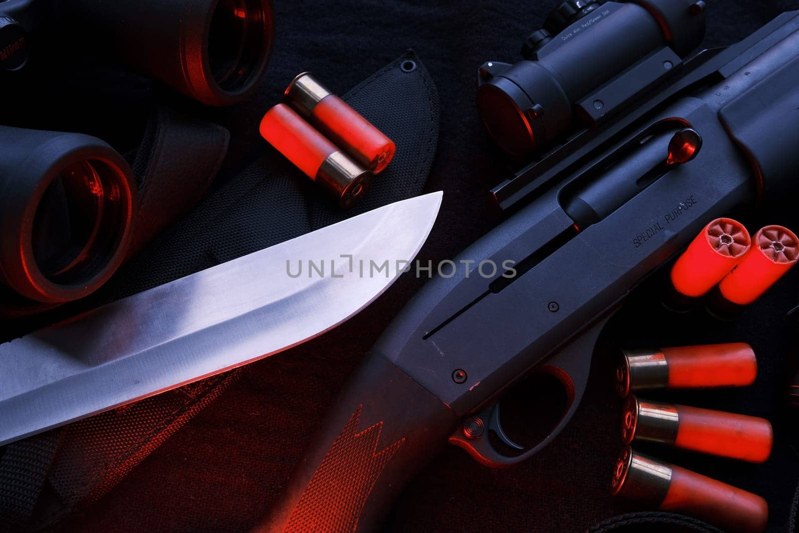 Weapon on black cloth: binoculars, flashlight, knife, rifle, shells,top view. Top view of knife rifle shells