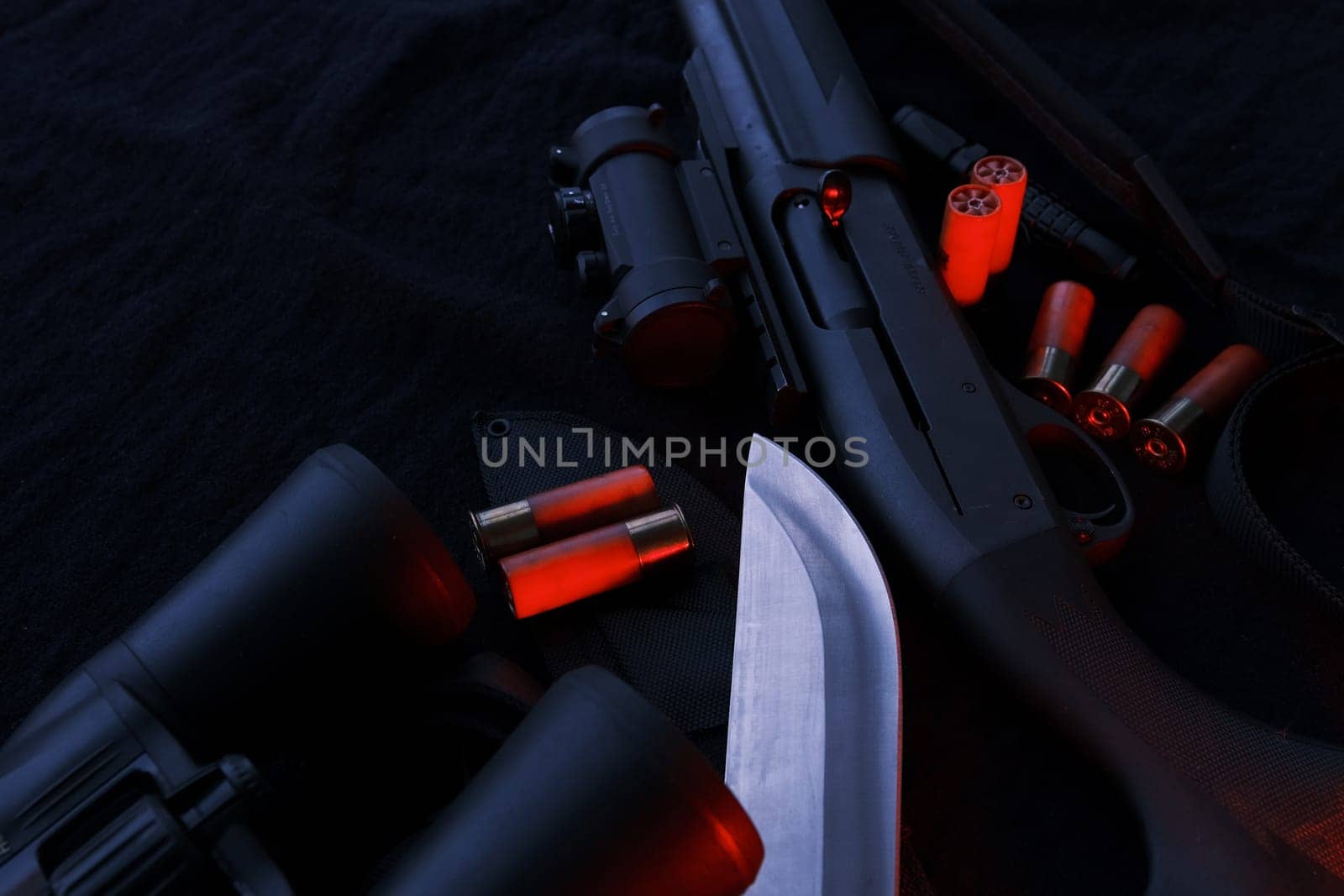 Weapon on black cloth: binoculars, flashlight, knife, rifle, shells,top view. Top view of knife rifle shells