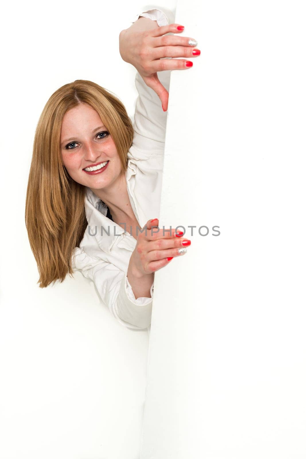 Young blond business woman peeking around a corner in white jacket over white backround