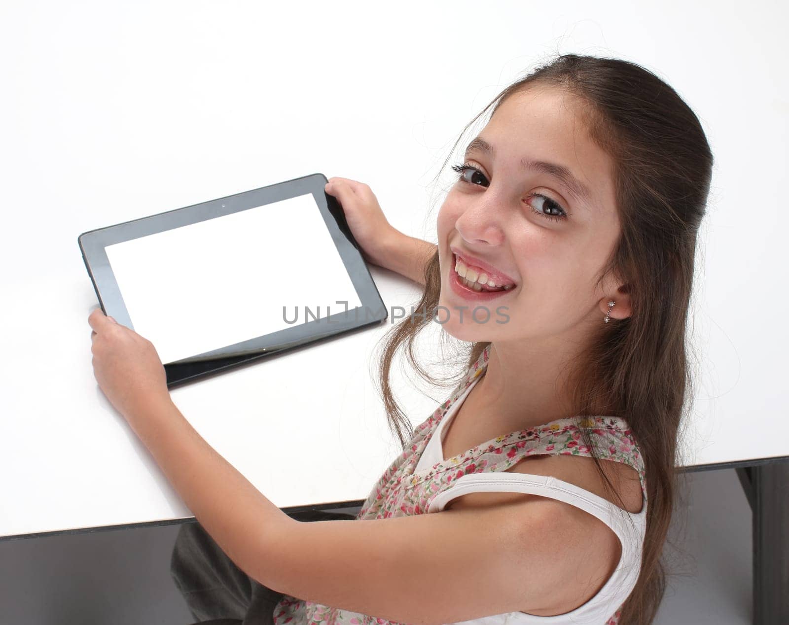 Beaitiful pre-teen girl using a tablet computer. High angle. Clipping path for the screen