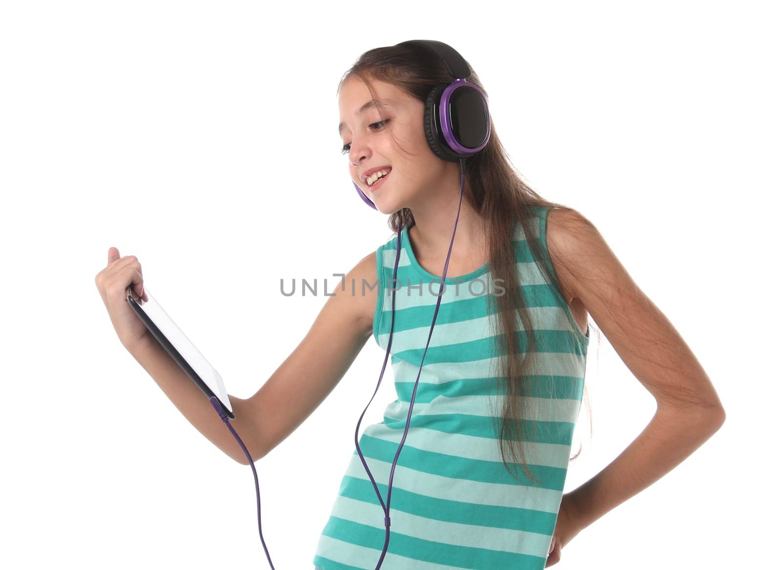 Beautiful pre-teen girl using a tablet computer and headphones. Isolated
