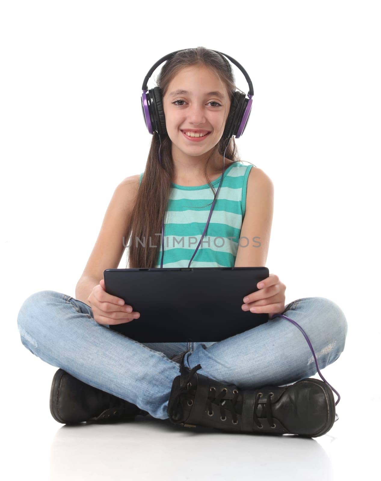 Beautiful pre-teen girl using a tablet computer and headphones.