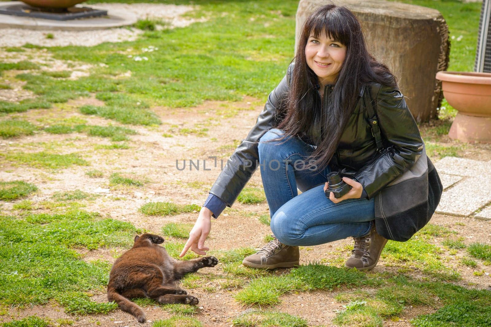 a girl playing in a garden with a black cat