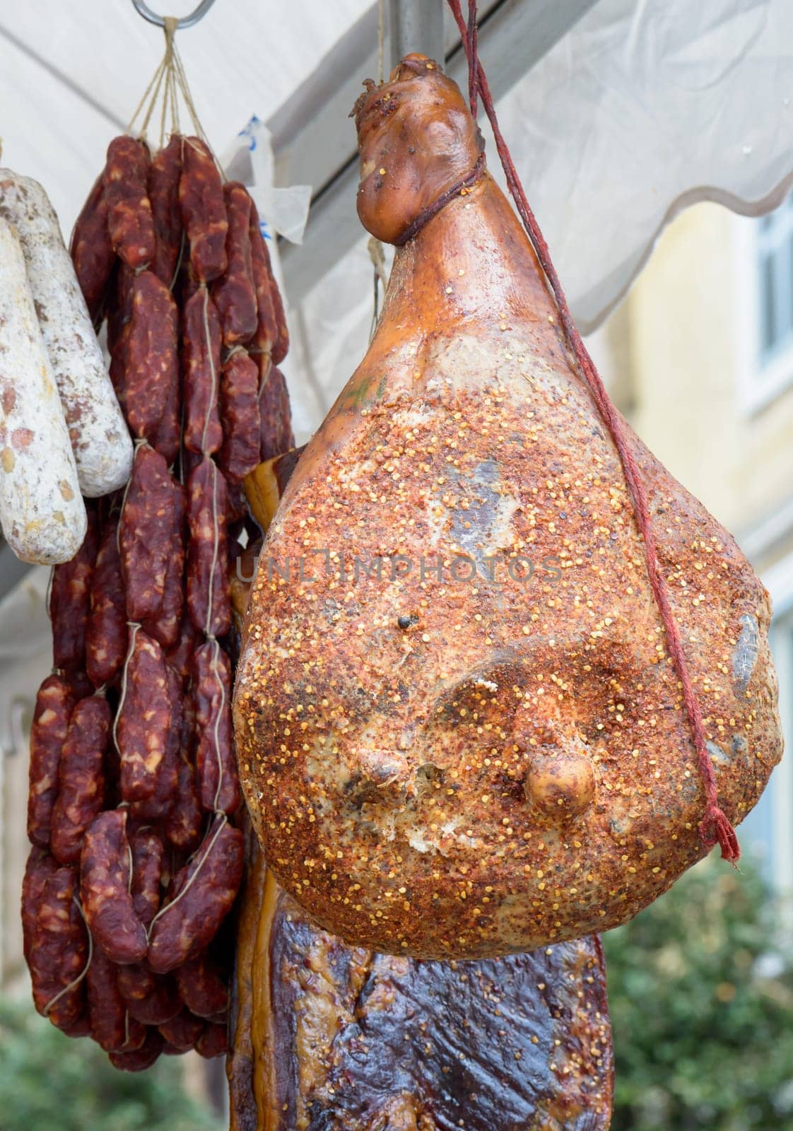 salami, ham and other meats for sale in a market in a village festival