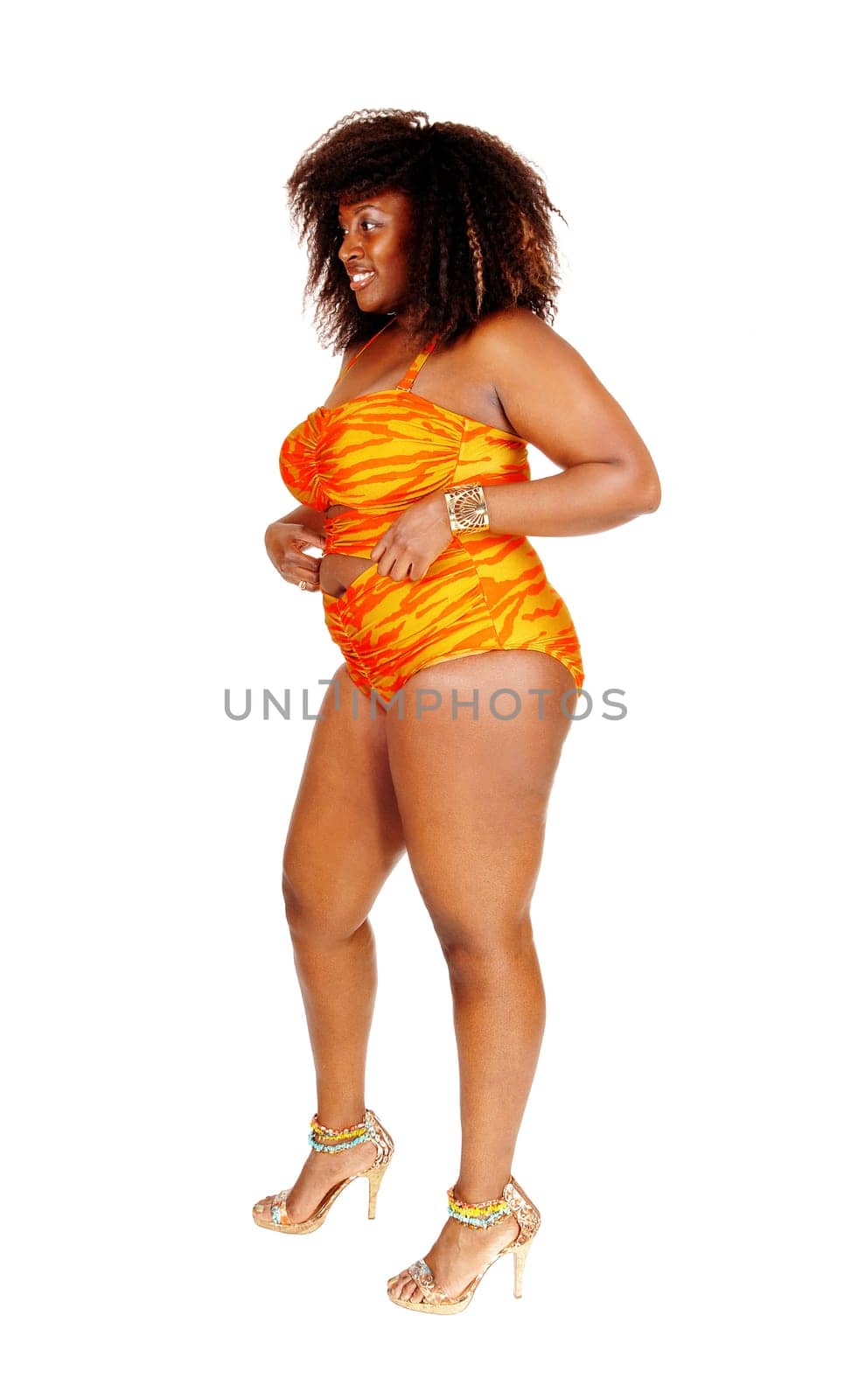 An African American young woman standing in profile in a orange bikini.on the floor, isolated for white background..