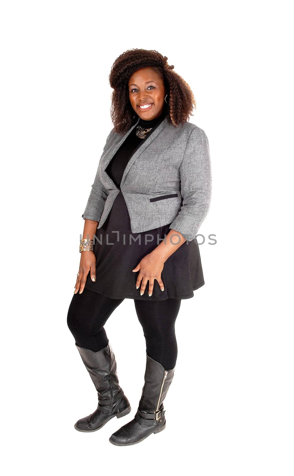 A full body picture of a young African American woman in a black dress.and grey jacket and boots, standing isolated for white background..