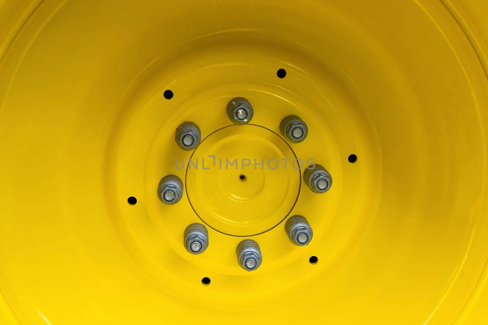Screwing on a large wheel rim of a tractor in detail.