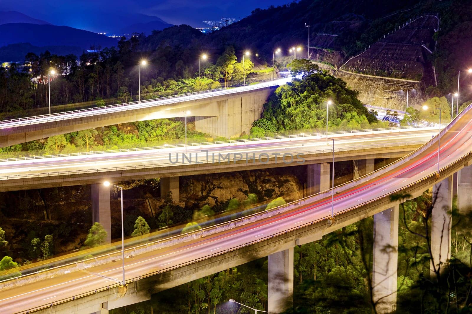 moving car on highway bridge with light through city at night