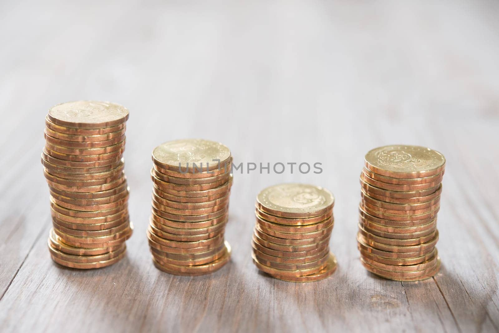Coins stack in row on wooden background, financial concept. Focus on foreground with blur background.