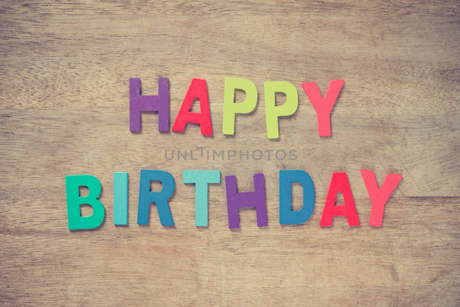 The colorful words "HAPPY BIRTHDAY"" made with wooden letters on old wooden plank."