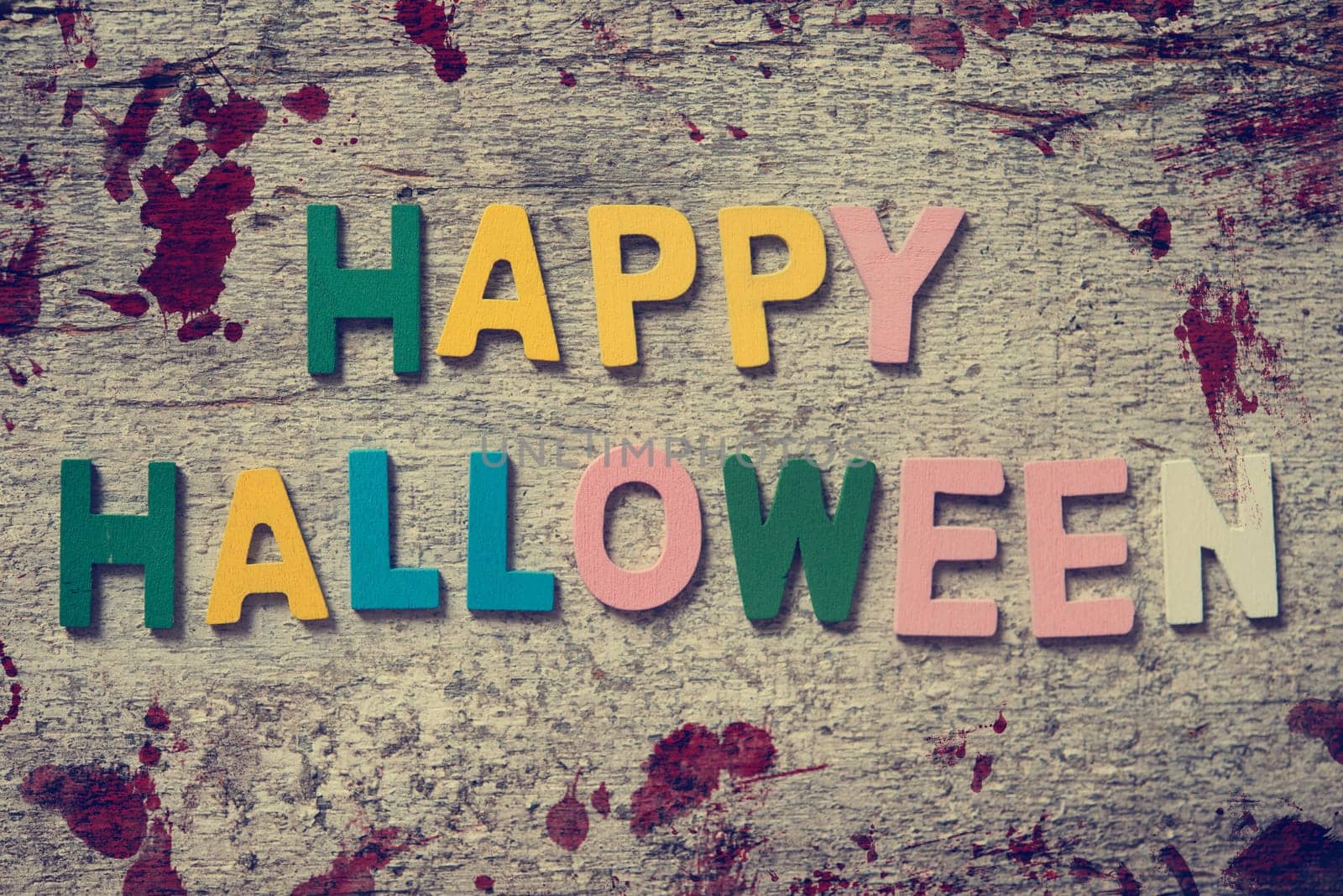 The colorful words "HAPPY HALLOWEEN"" made with wooden letters on old wooden board."