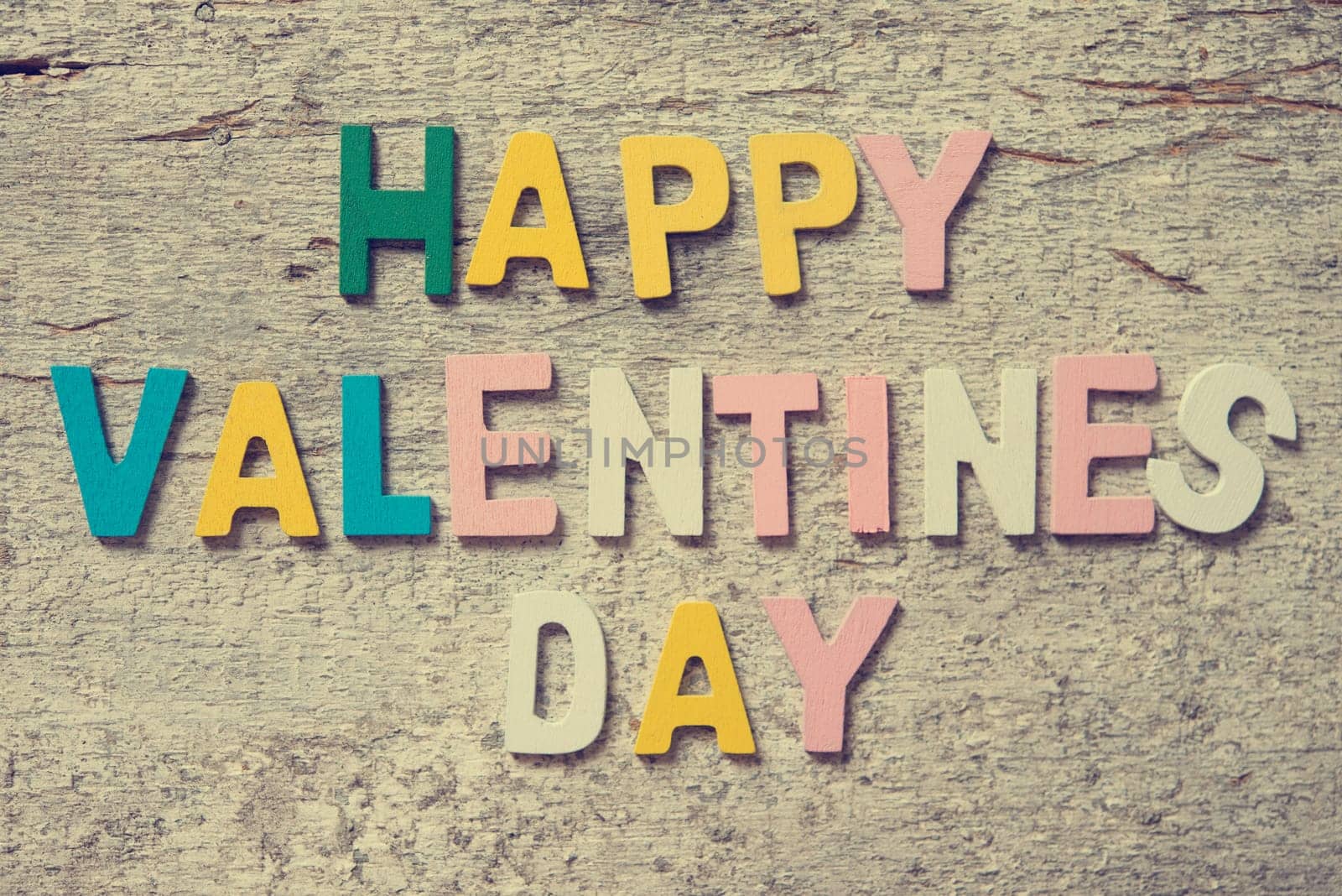 The colorful words "HAPPY VALENTINES DAY"" made with wooden letters on old wooden board."