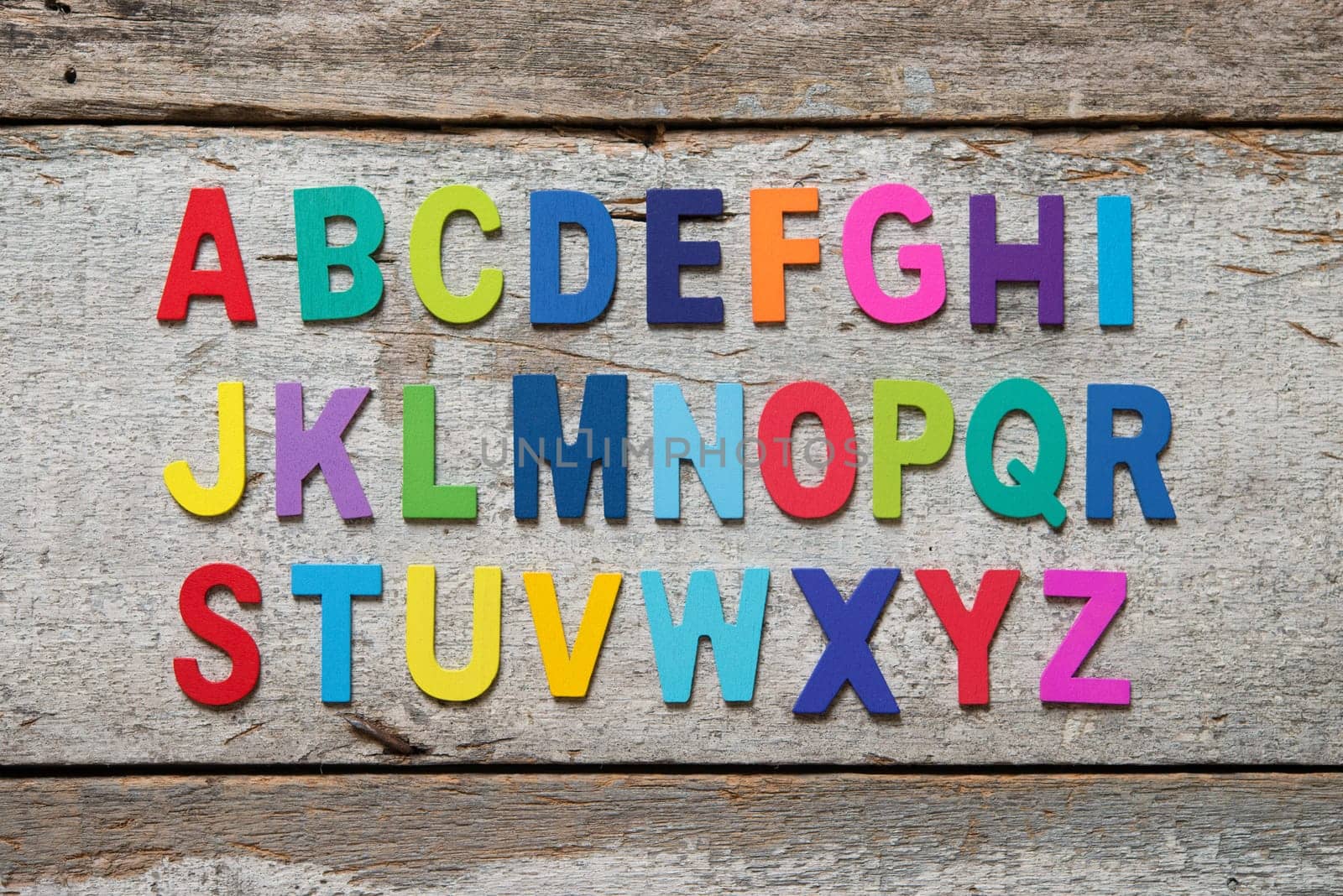 Colorful wooden English alphabet set on grunge wooden background.