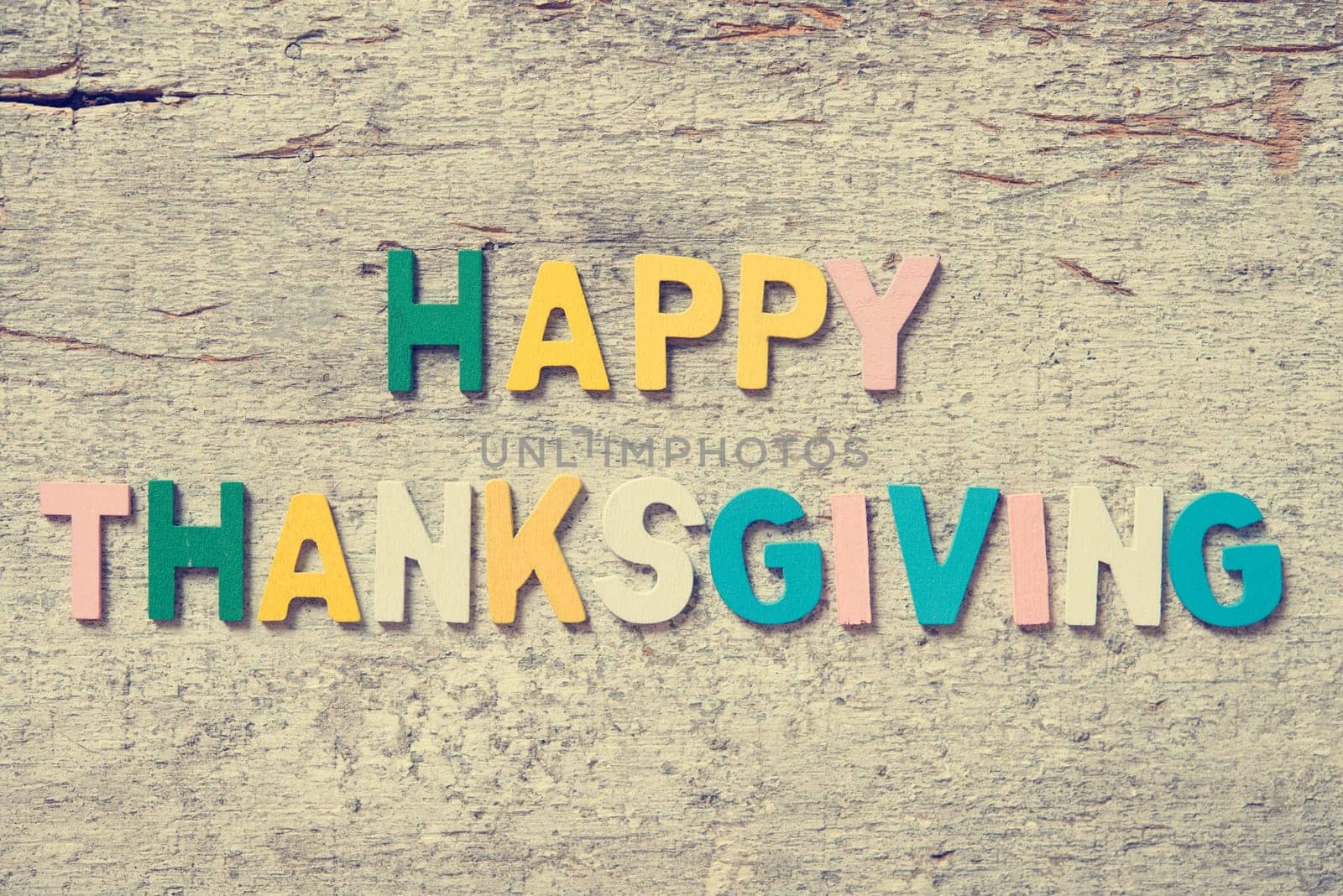 The colorful words "HAPPY THANKSGIVING"" made with wooden letters on old wooden plank."