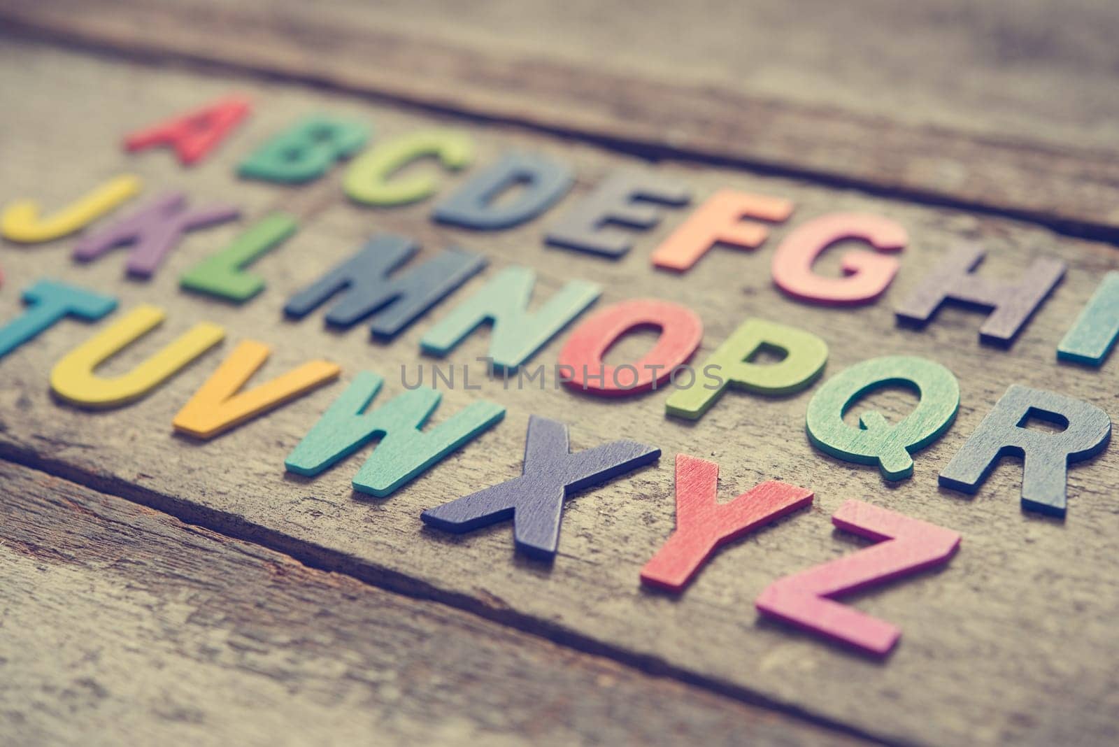 Colorful wooden English alphabet set on grunge wooden background, focus on alphabet X.