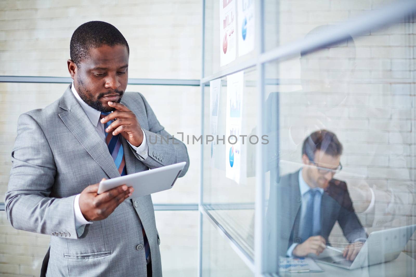 Pensive businessman with touchpad studying data for project