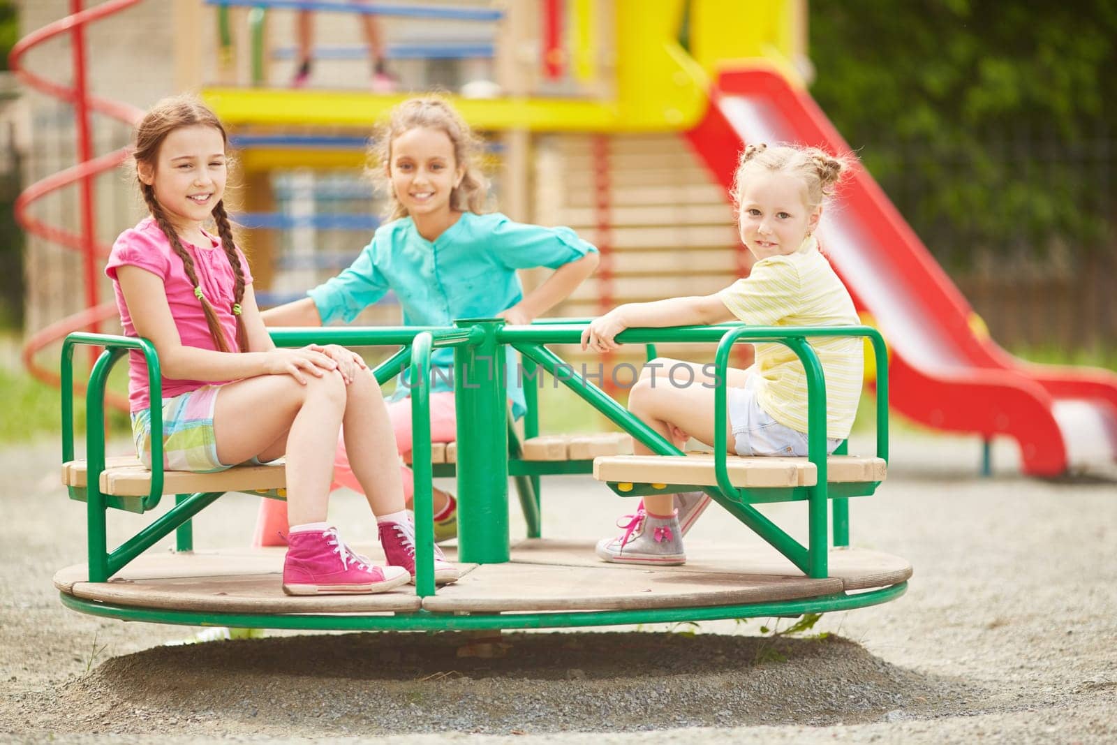 Friendly girls riding on carousel at leisure