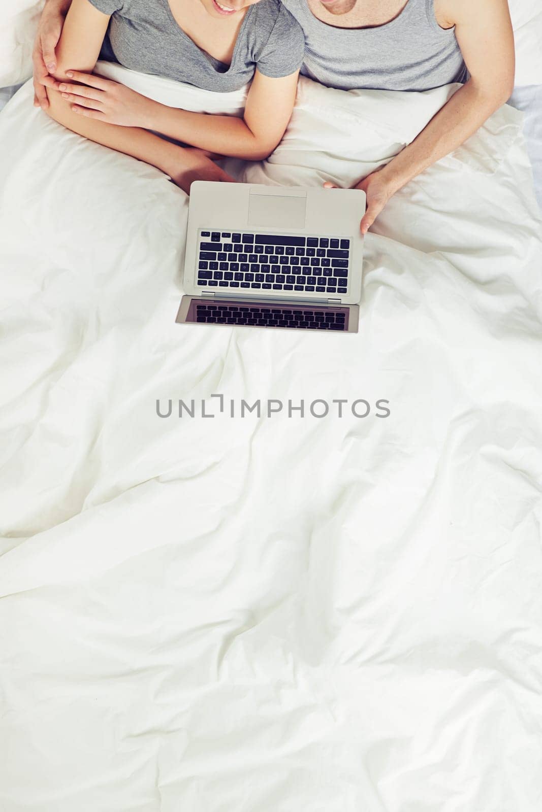 Young couple sitting in bed with laptopv