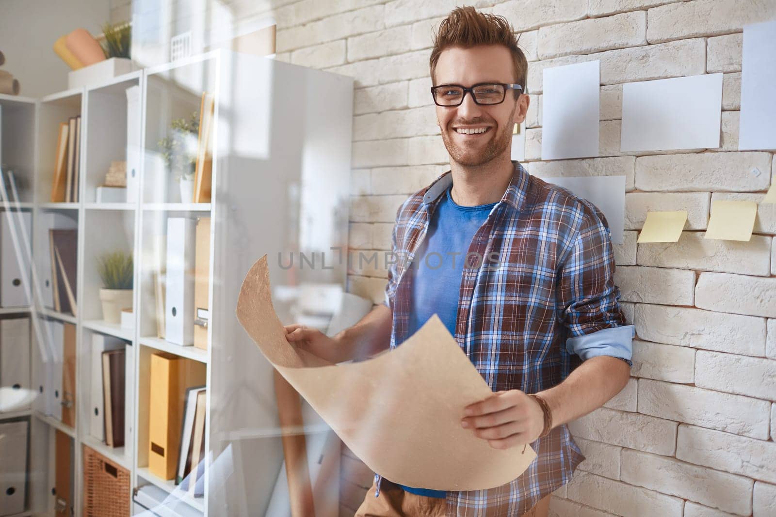 Happy businessman with document looking at camera by the wall