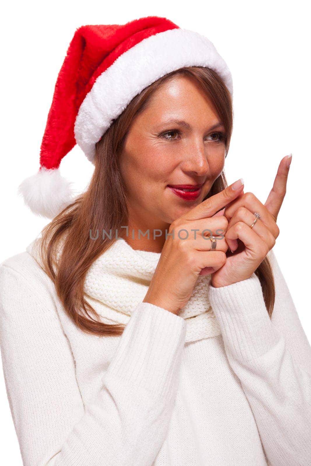 Young attractive woman with red Christmas hat points her finger in one direction isolated on white background