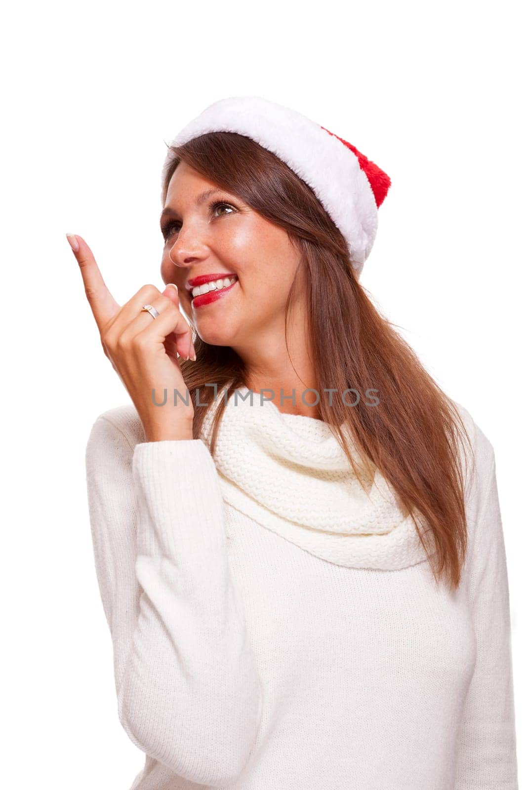 Young attractive woman with red Christmas hat points her finger in one direction isolated on white background